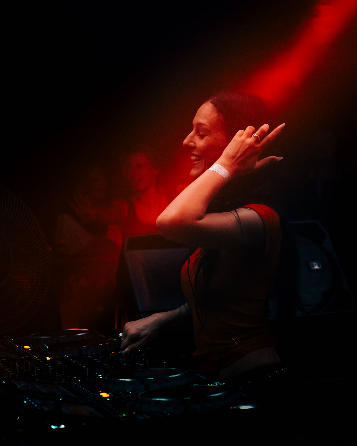 DJ mixing under a red spotlight at a KompaanEvents night