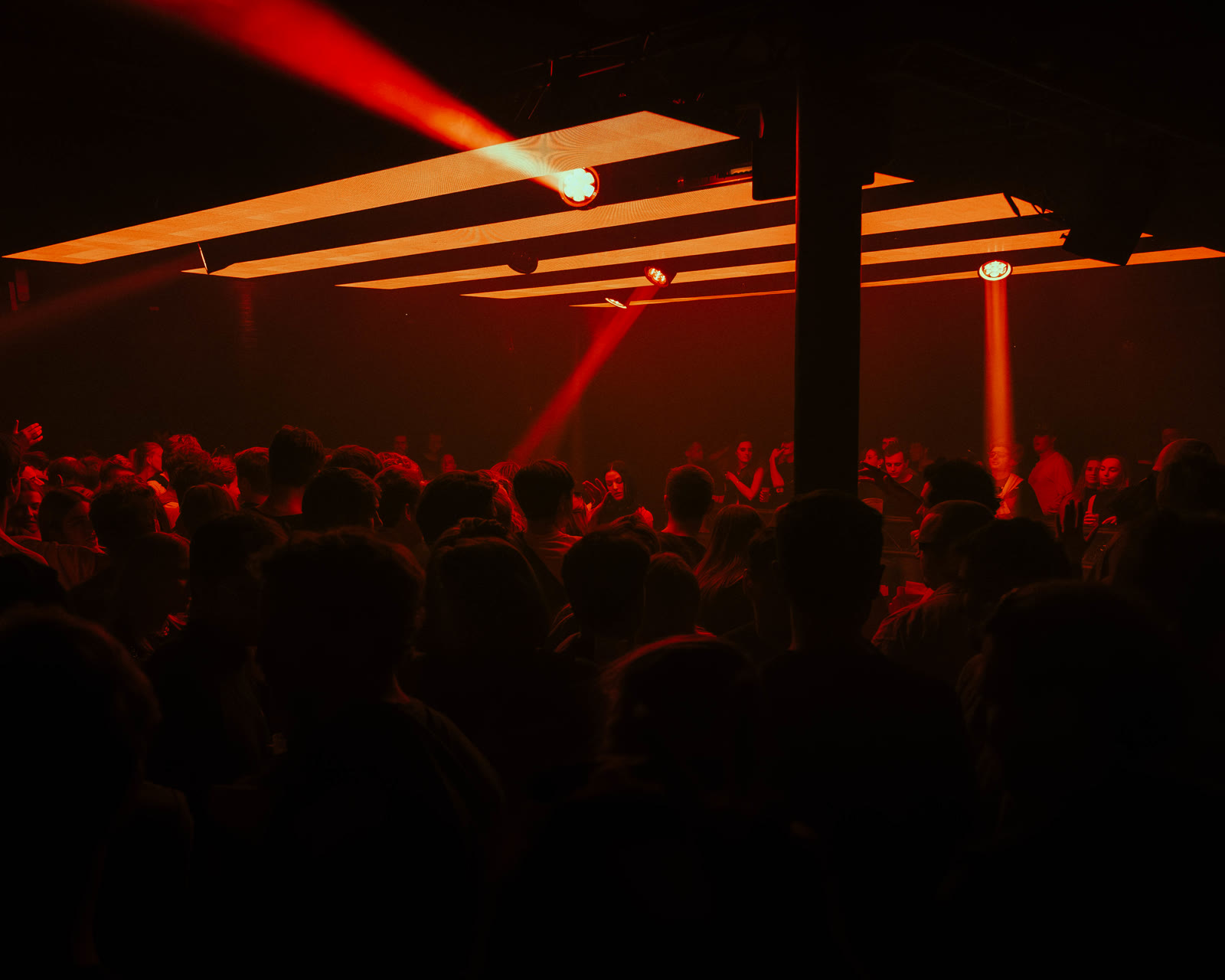 Crowd on the dancefloor under red light beams at a KompaanEvents night