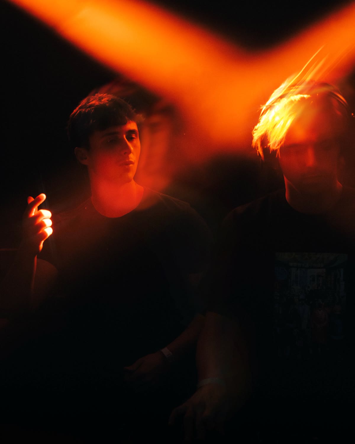 Two guests lit by crossing orange stage lights at a KompaanEvents night