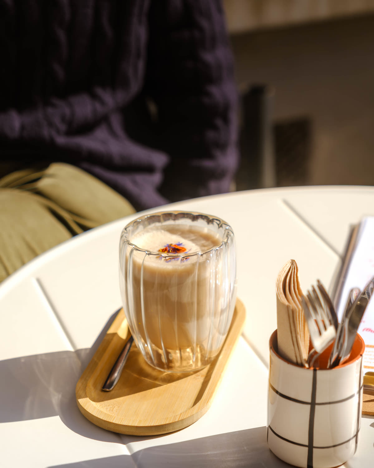 Latte topped with edible flowers on a wooden tray at TheSpot